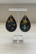 Boucles d’oreilles lucioles pégase et licorne sur présentoir ivoire