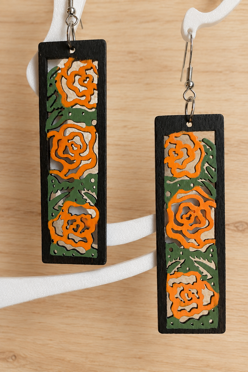 Boucles d’oreilles en bois peint roses orangées sur présentoir