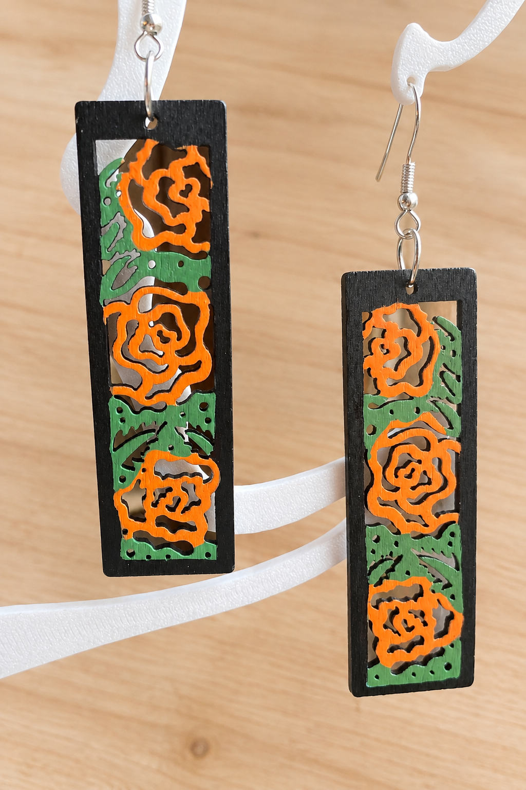 Boucles d’oreilles en bois peint roses orangées sur présentoir