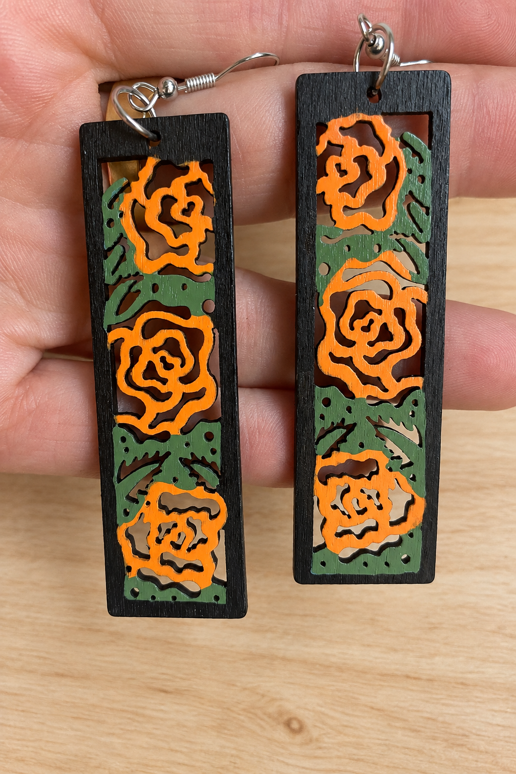 Boucles d’oreilles en bois peint roses orangées sur fond bois clair