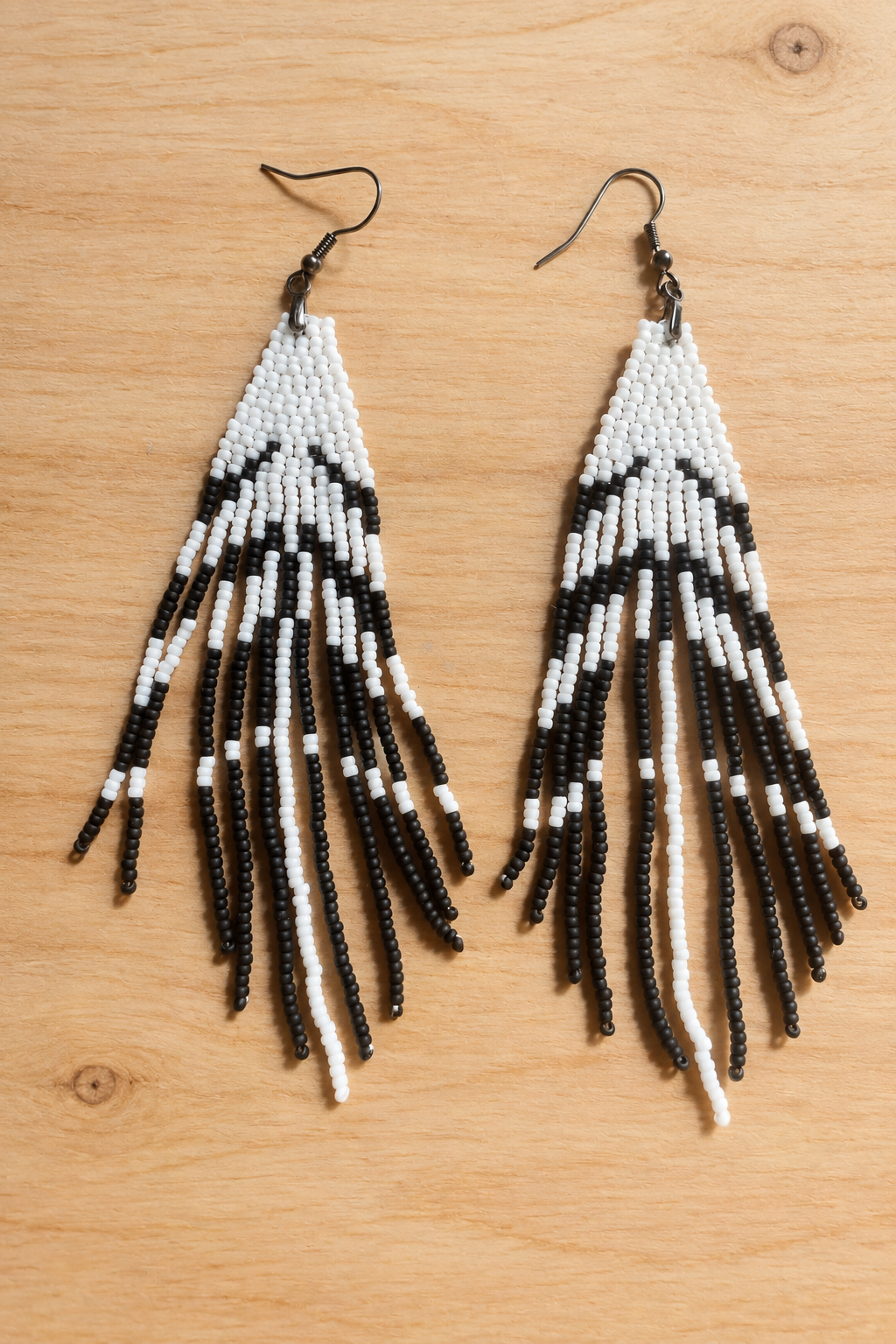 Boucles d’oreilles longues blanches et noir mat sur fond bois clair
