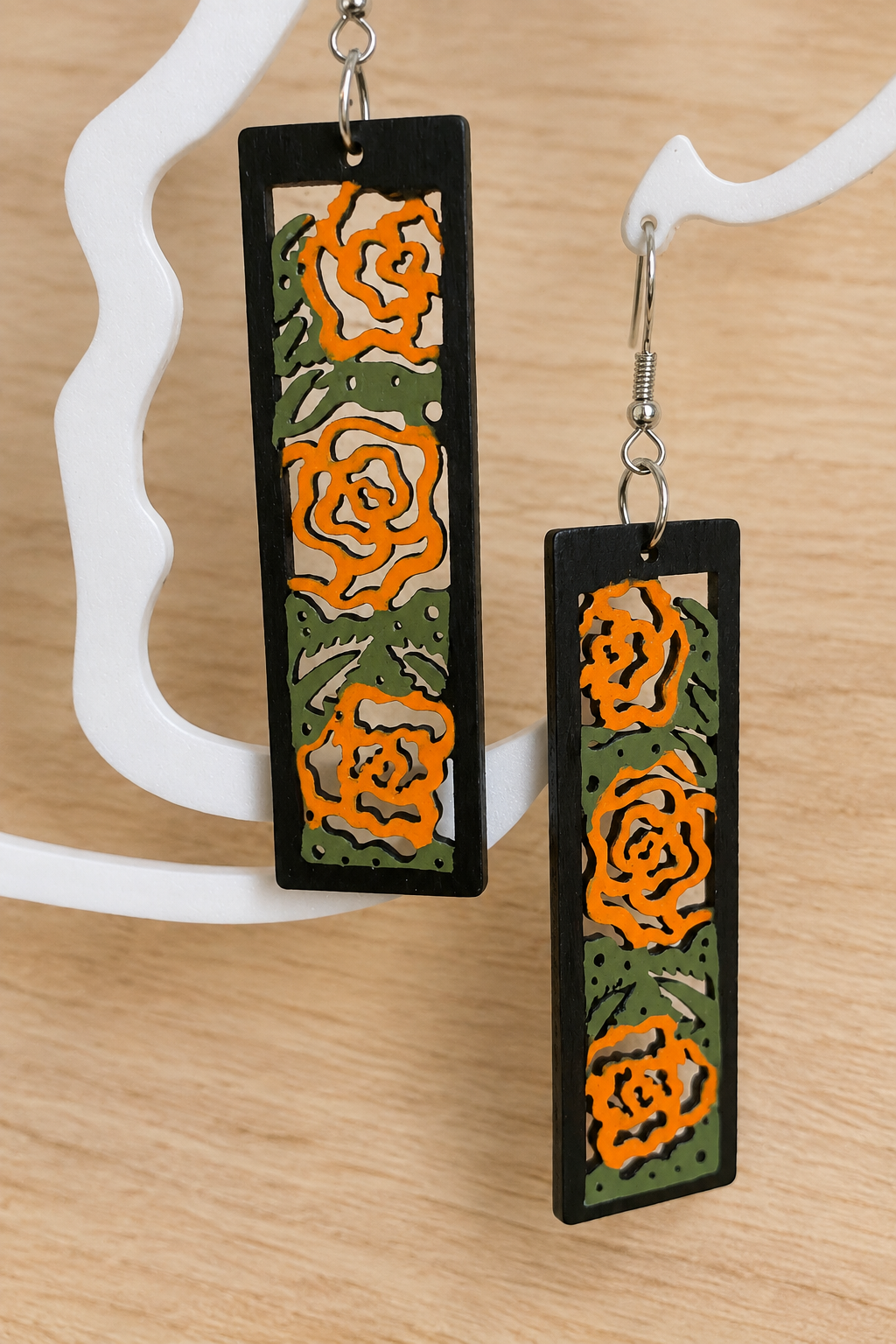 Boucles d’oreilles en bois peint roses orangées sur présentoir