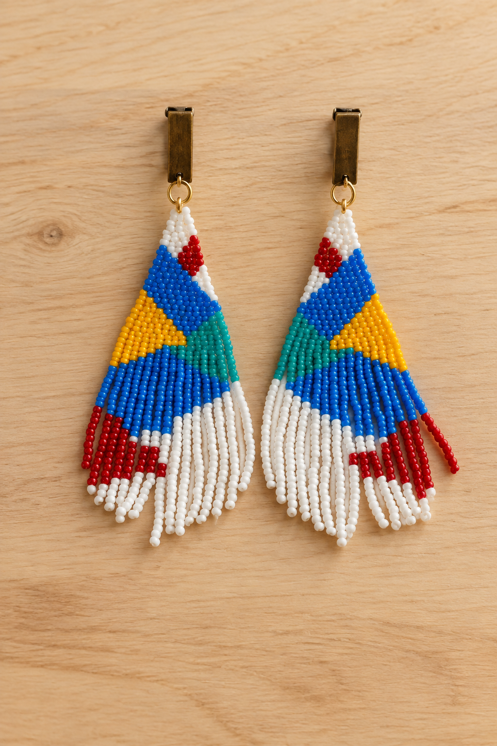 Boucles d’oreilles pendantes géométriques mauve et multicolores en perles Miyuki sur fond bois clair