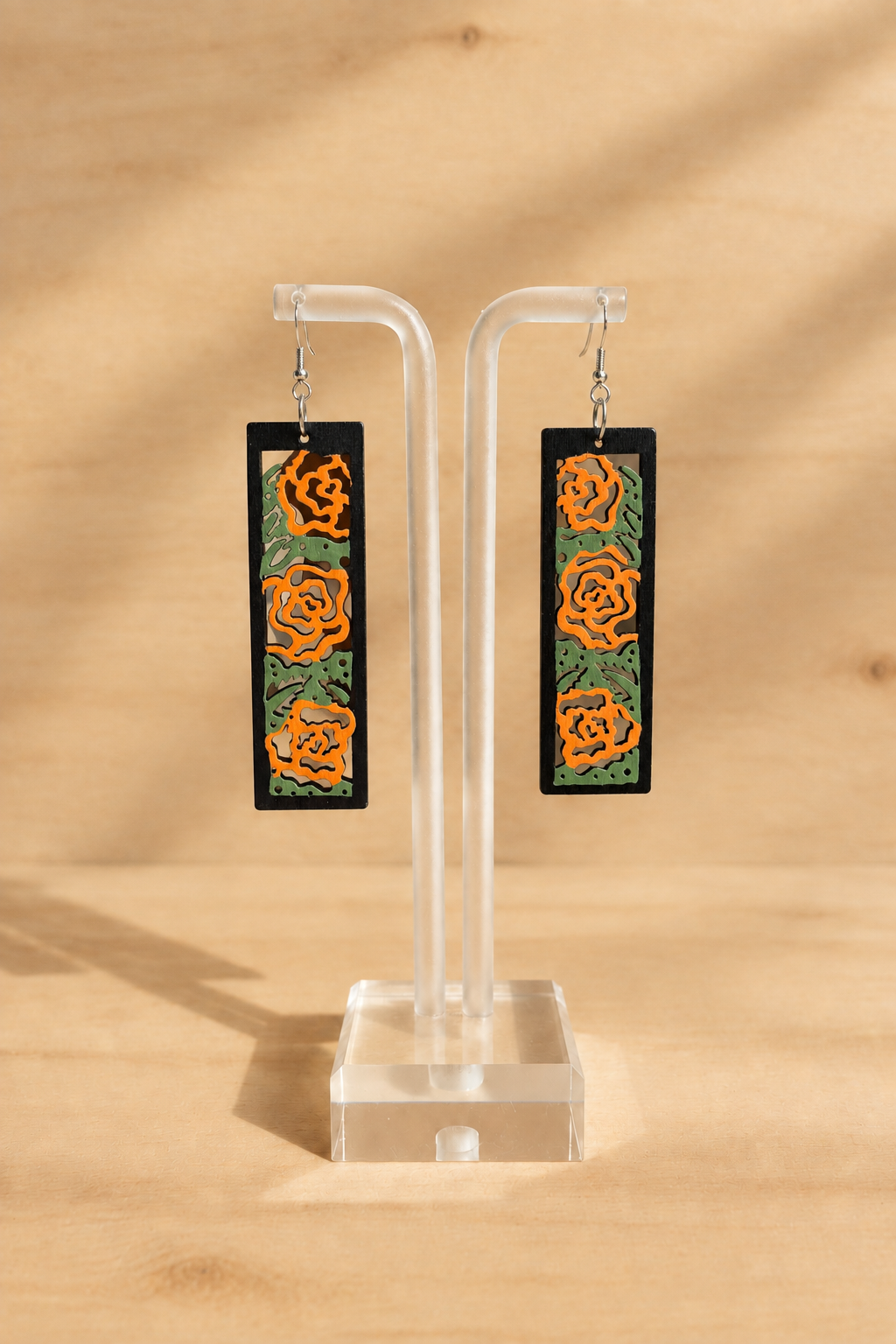 Photo de présentation des boucles d’oreilles en bois peint roses orangées sur présentoir