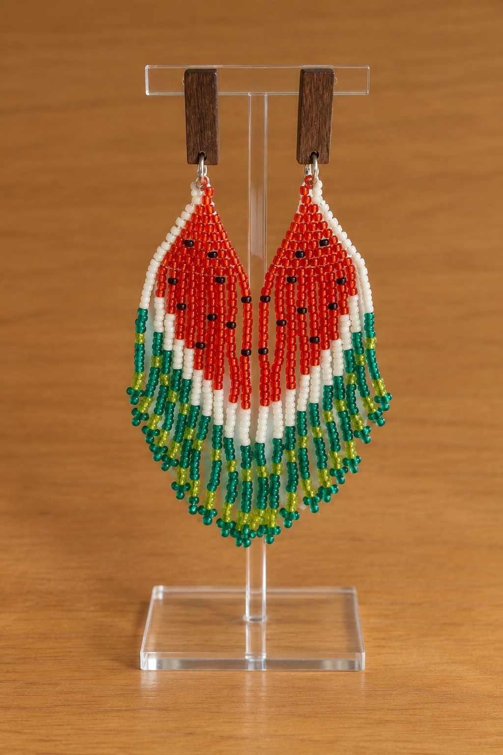Boucles d’oreilles Miyuki pastèque rouge et vert sur présentoir transparent, fond bois clair