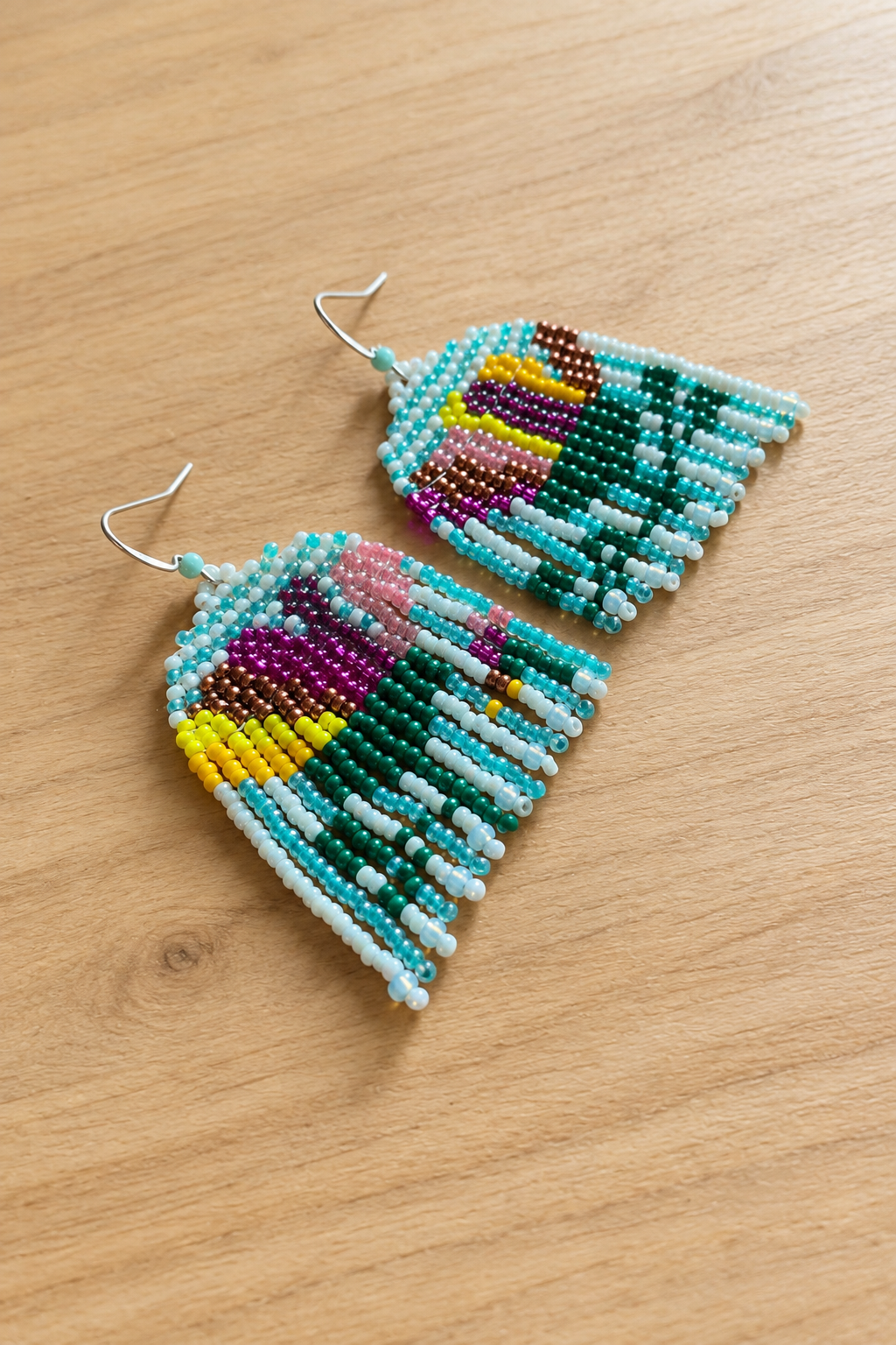 Boucles d’oreilles pendantes multicolores sur fond bois clair