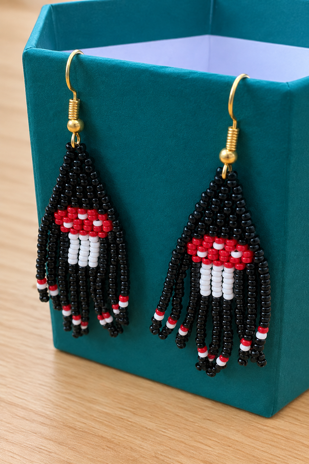 Boucle d’oreille pendante noire en perles Miyuki, motif champignon, sur fond bois clair