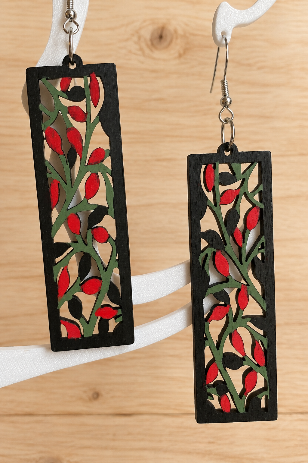 Boucles d’oreilles en bois peint branches et baies rouges sur présentoir