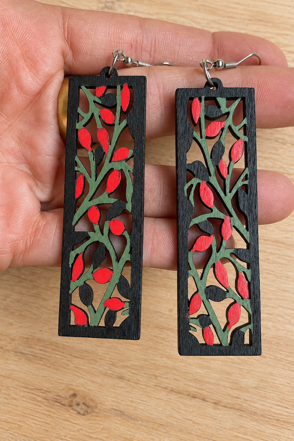 Boucles d’oreilles en bois peint branches et baies rouges sur fond bois clair