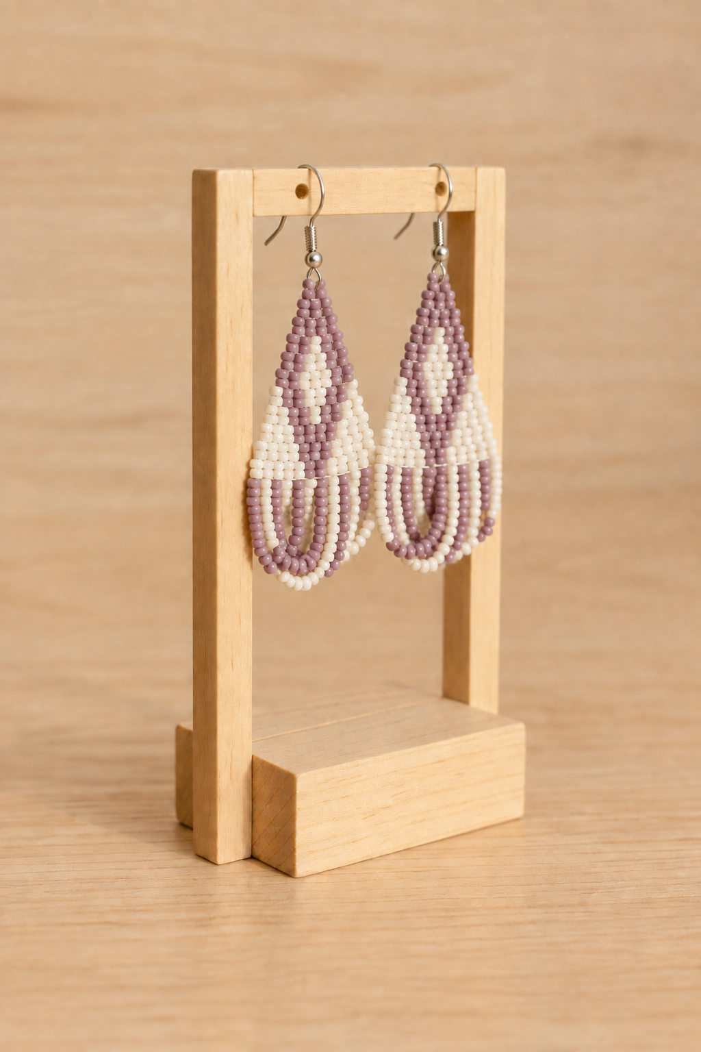 Boucles d’oreilles triangle crème mauve lilas sur présentoir en bois clair, fond bois clair