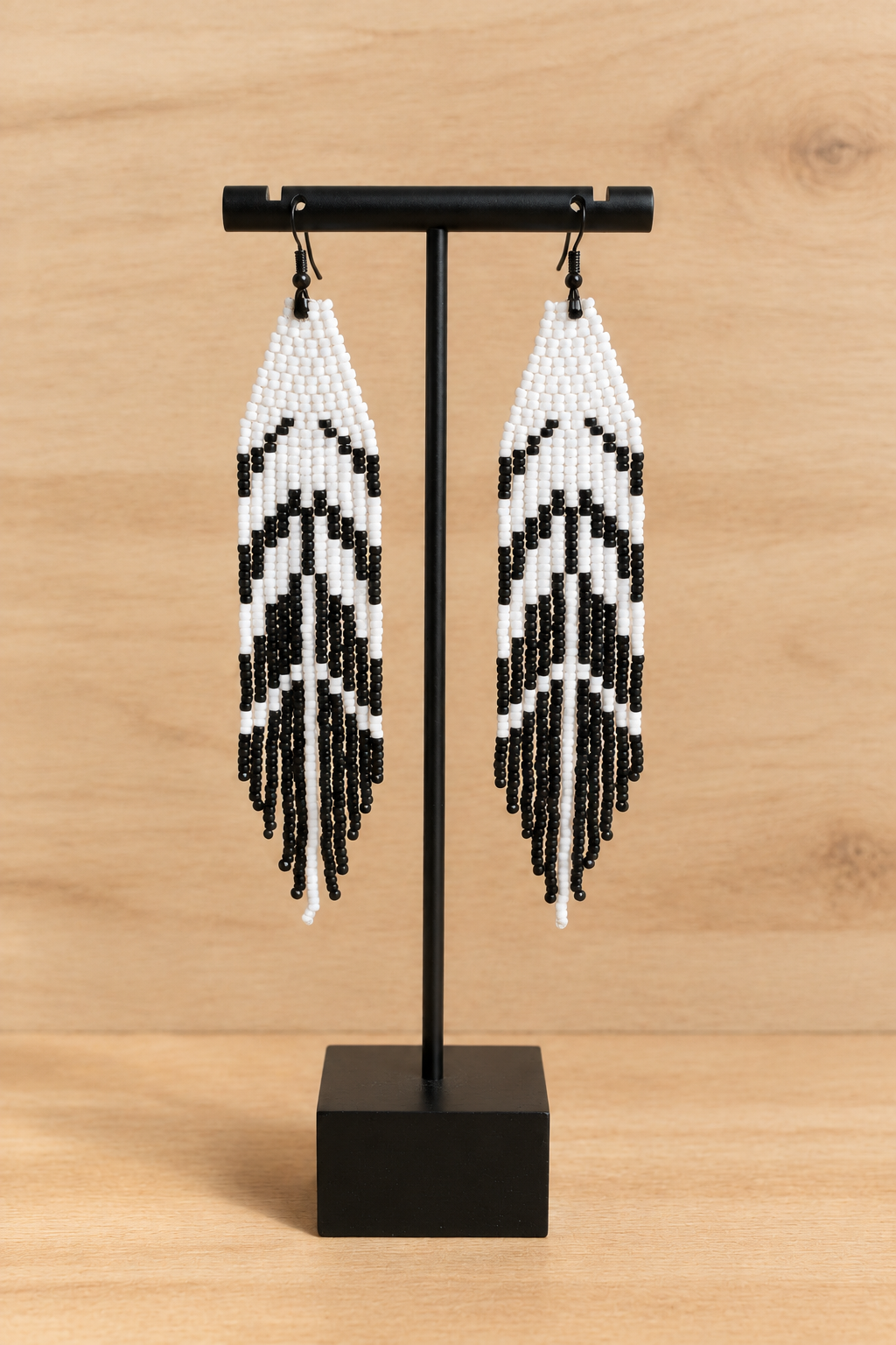 Boucles d’oreilles longues blanches et noir mat sur fond bois clair
