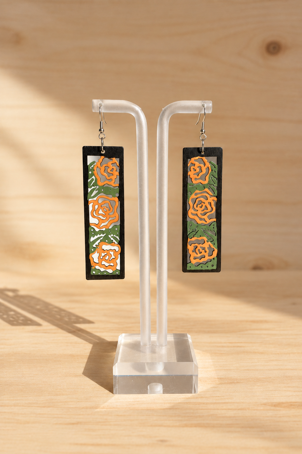 Boucles d’oreilles en bois peint roses orangées sur présentoir