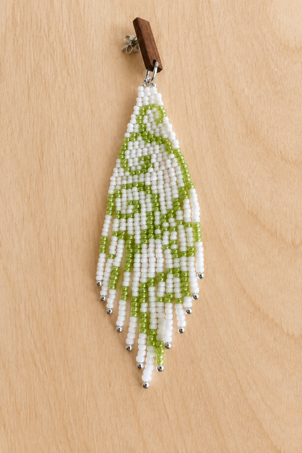 Boucle d’oreille pendante vert clair en perles Miyuki sur fond bois clair