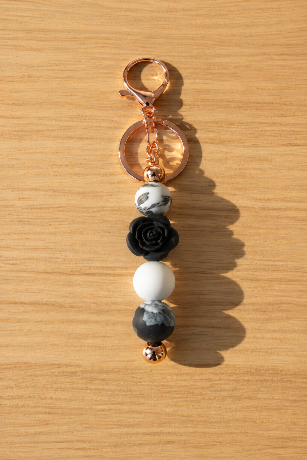 Bijou de sac rose blanche et noire et attache cuivrée, sur fond bois assorti à la photo de présentation