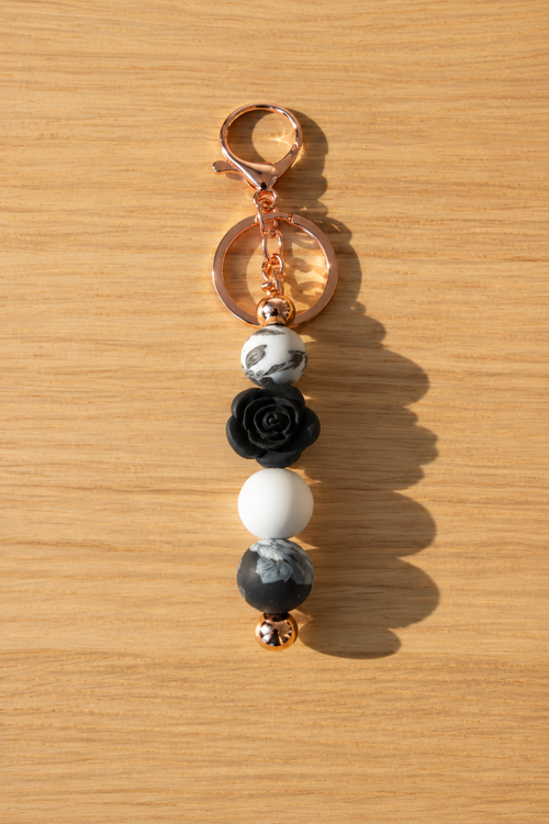 Bijou de sac rose blanche et noire et attache cuivrée, sur fond bois assorti à la photo de présentation