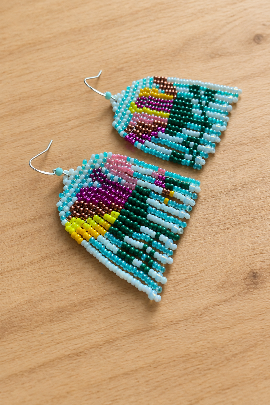 Boucles d’oreilles pendantes multicolores sur fond bois clair