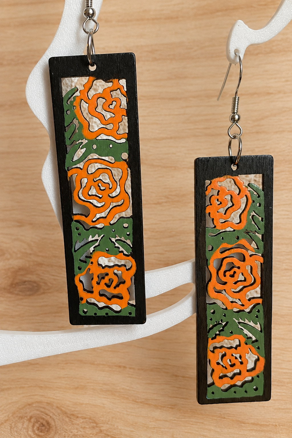 Boucles d’oreilles en bois peint roses orangées sur présentoir