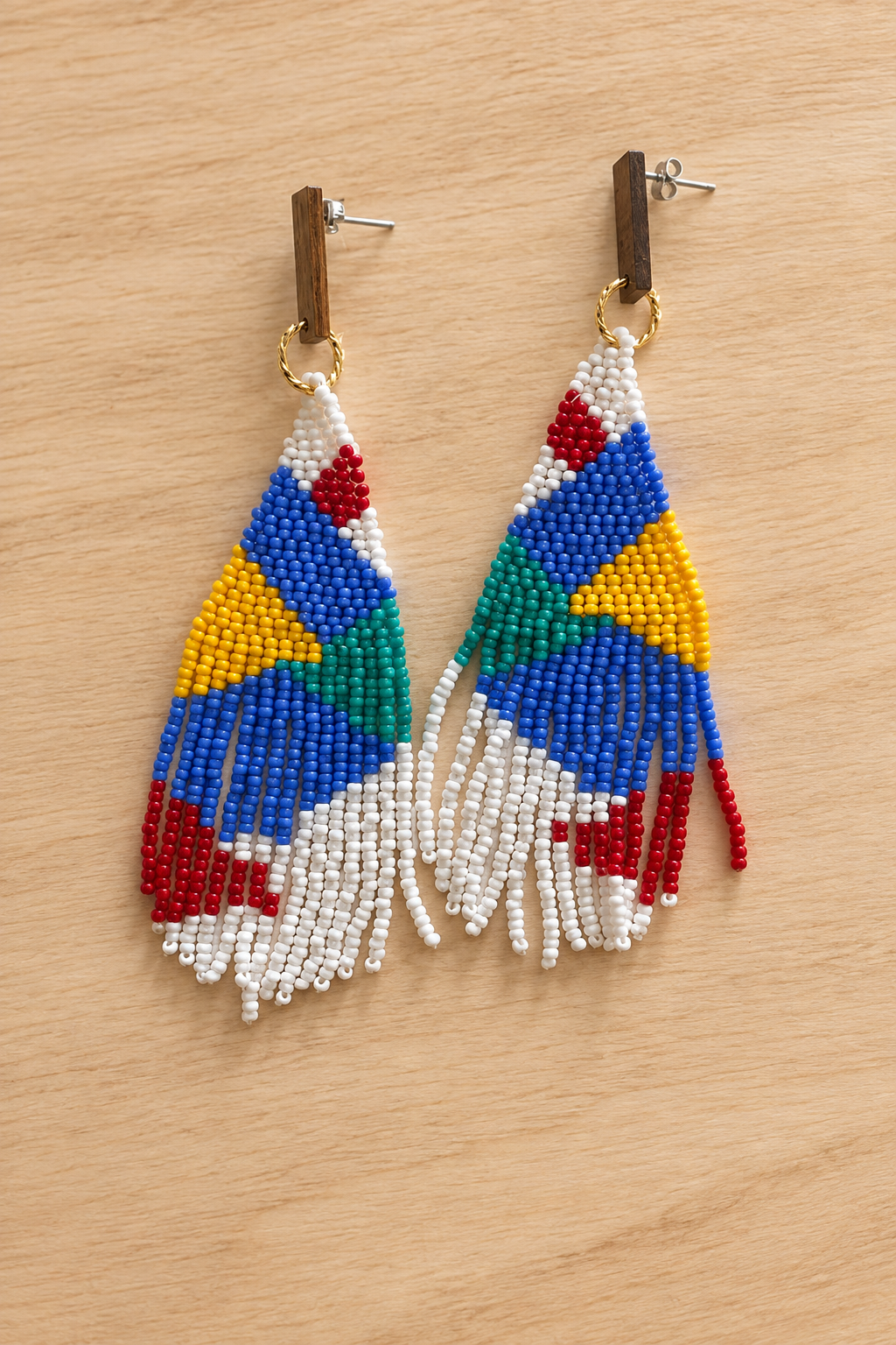 Boucles d’oreilles pendantes géométriques mauve et multicolores en perles Miyuki sur fond bois clair