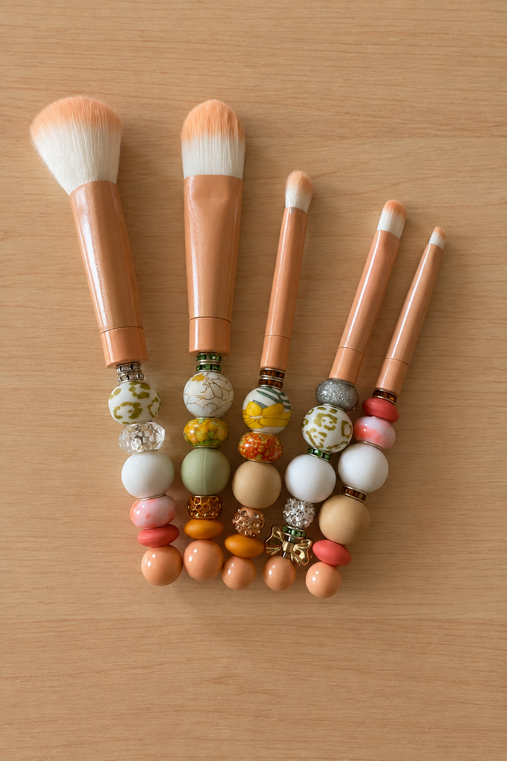 Lot de cinq pinceaux à maquillage pêche en perles et strass sur bois clair