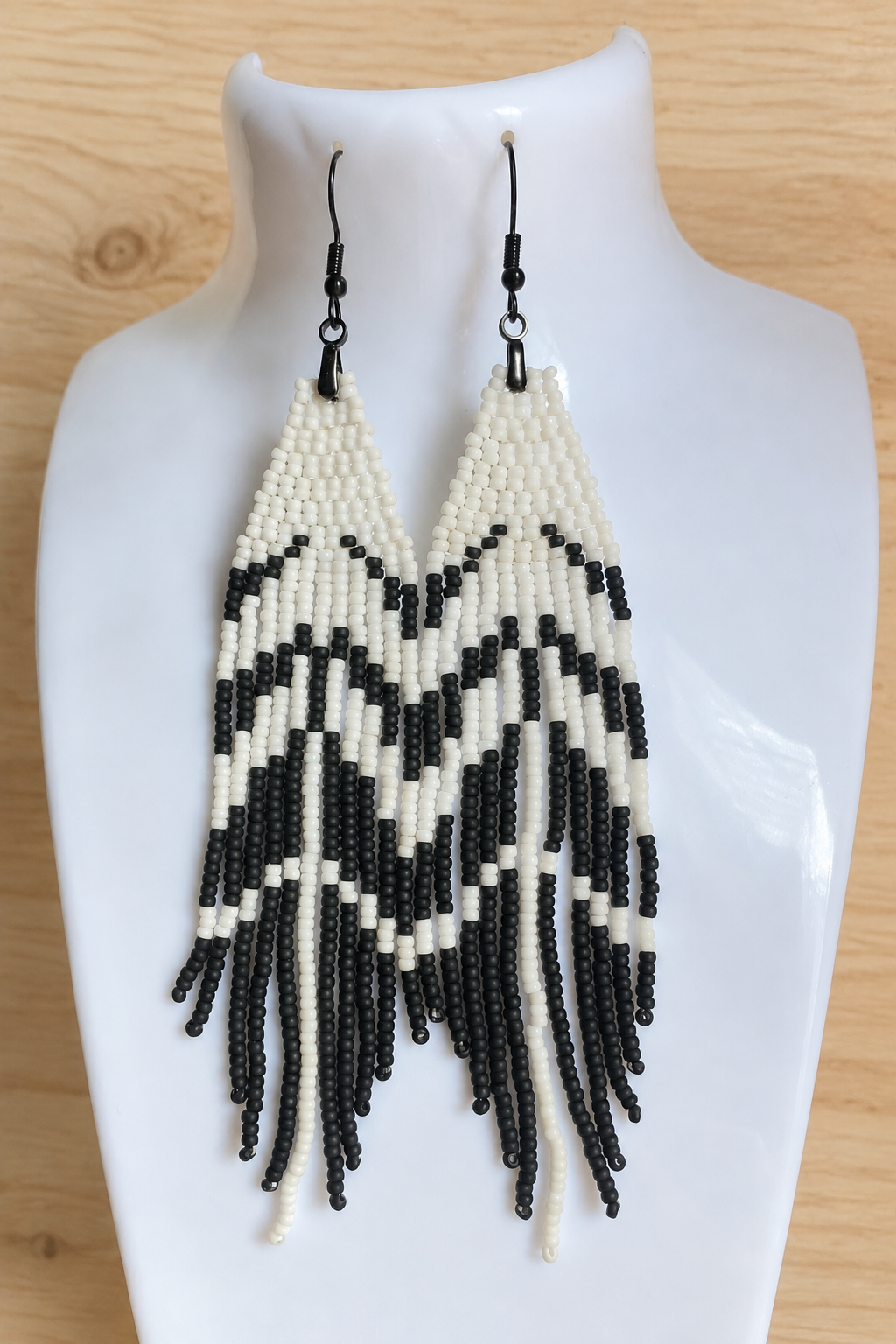 Boucles d’oreilles longues blanches et noir mat sur fond bois clair