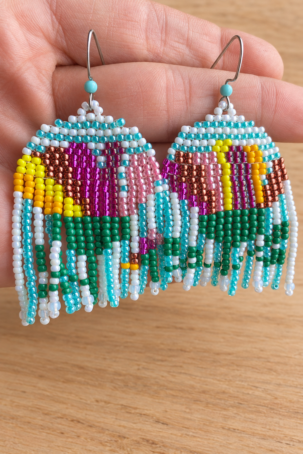 Boucles d’oreilles pendantes multicolores sur fond bois clair