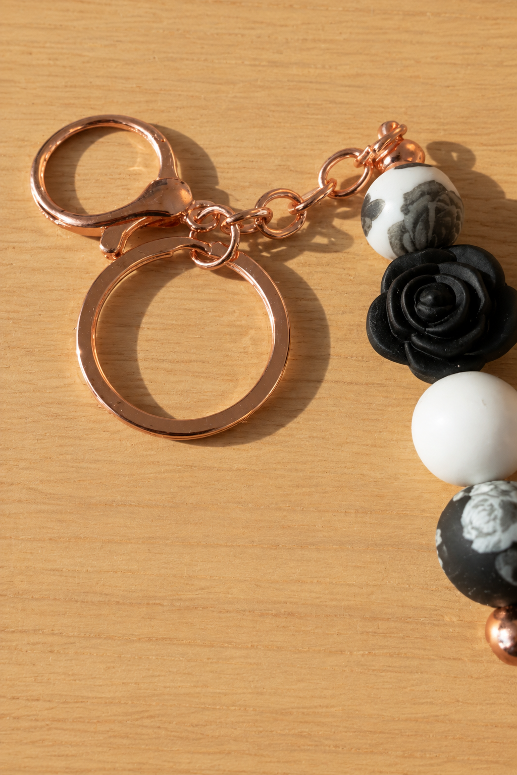 Bijou de sac rose blanche et noire avec attache cuivrée, vue rapprochée sur fond bois assorti
