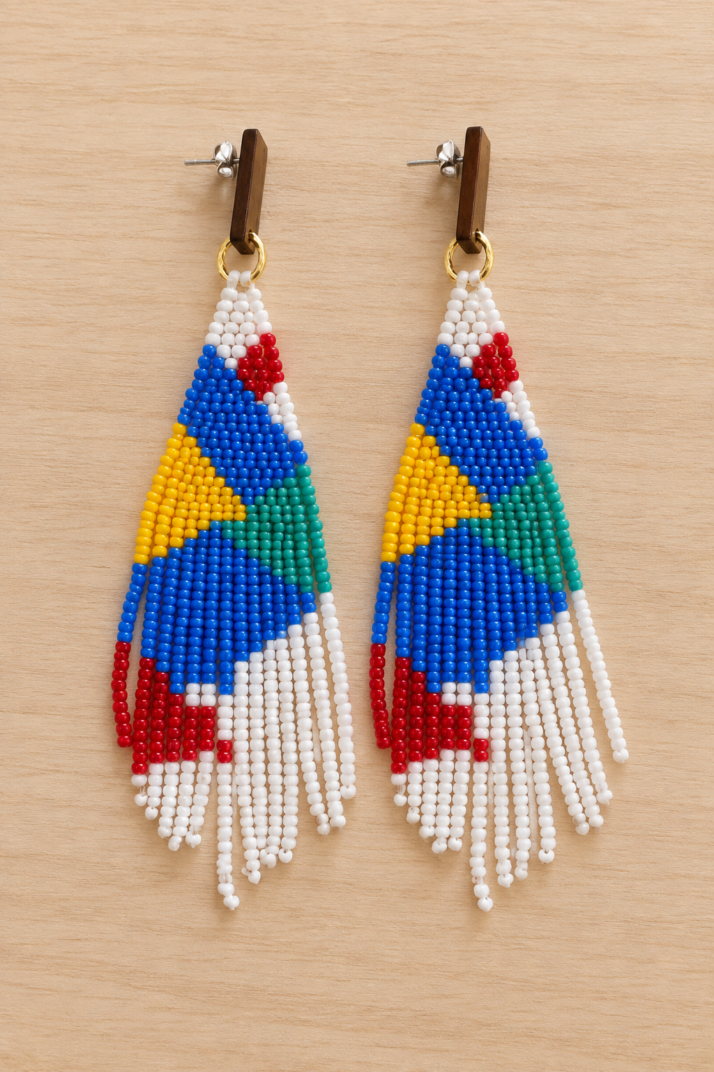 Boucles d’oreilles pendantes géométriques mauve et multicolores en perles Miyuki sur fond bois clair